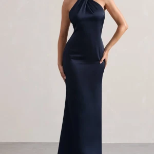 Mörkblå långklänning med halterneck - Elegant mörkblå långklänning i satin med halterneck-design och öppen rygg. Perfekt för en stilren och sofistikerad look. Klänningen har en smickrande passform som framhäver figuren. Den är helt ny och oanvänd med prislapp kvar.