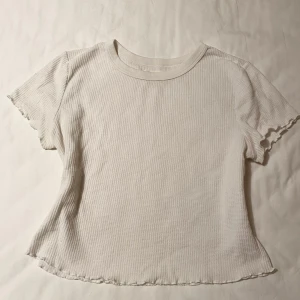 Vit ribbad topp från Twintip - Säljer en vit ribbad topp från Twintip med korta ärmar och vågig kant. Passar bra till jeans eller kjol. Finns ingen storlek i den, men skulle säga XS/S Kontakta mig om du har frågor🥰