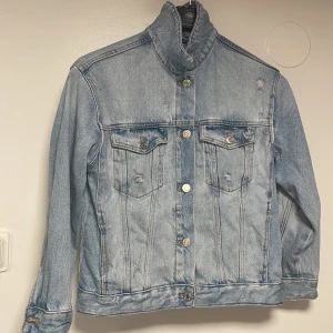 Ljusblå jeansjacka från Zara - Säljer en snygg ljusblå jeansjacka från Zara i storlek 140. Jackan har knappar framtill och två bröstfickor med knappstängning. Perfekt för en avslappnad stil. 🧢👖
