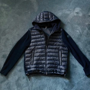 Mörkblå Colmar Cardigan - Säljer en mörkblå cardigan från Colmar med quiltad framsida och huva. Jackan har dragkedja. Perfekt för kyligare dagar! Stlk 54/L. Har fler bilder så det är bara att skriva och fråga!