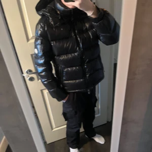 Svart Monclear maya från Moncler - Säljer en snygg svart dunjacka från Moncler. Jackan har en glansig finish och är utrustad med en huva. Den har dragkedja framtill och två fickor med dragkedjor. Perfekt för kalla dagar! Denna jacka är storlek ”2” vilket är snarlikt till S. Kontakta mig vid frågor om produkten, pris kan diskuteras vid effektiv affär, tar även byten för monclear cardigan.