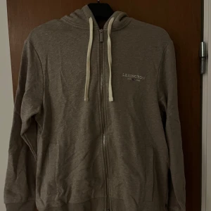 Beige hoodie från Lexington - Säljer en stilren beige hoodie från Lexington med dragkedja och justerbar huva. Tröjan är använd 1-2 gånger då jag tycker den blev lite väl lång på mig. Det är en oversize tröja i storlek S alternativt att den funkar bra i längd på en längre person. Tröjan är köpt på miinto.se för 1420 kr. Pris går att diskutera