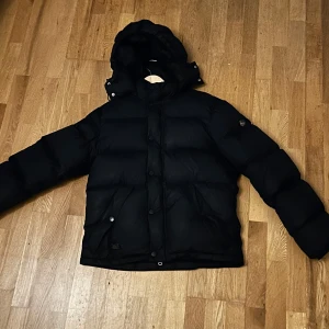 Morris Bromley Down Jacka - Säljer en stilren svart dunjacka från Morris. Jackan är  varm som gör den perfekt för kalla dagar. Den har inte varit använd så det finns inga slitage eller defekter. Hör gärna av er för mer information. Nypris: 3499kr