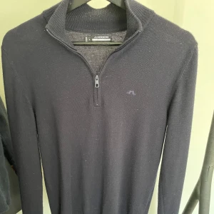 Mörkblå halfzip från J.Lindeberg - Snygg mörkblå tröja från J.Lindeberg med halv dragkedja. Perfekt för en stilren look, oavsett tillfälle. Tröjan är i storlek S. Hör av dig vid frågor eller fler bilder