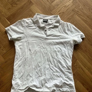 Vit piké t-shirt från Massimo Dutti - Vit piké t-shirt från Massimo Dutti med klassisk krage och knappar vid halsen. Kortärmad och i mjukt bomullsmaterial. 