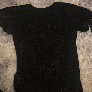 Svart tröja med puffärm och små prickar - Säljer en svart tröja med kort puffärm och små glittriga prickar över hela tyget. köpte tröjan i polen