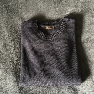 Stenströms - Säljer en klassisk blå/grå stickad tröja från Stenströms. Tröjan har rund halsringning med ribbade muddar vid hals, ärmslut och nederkant. Enkel att matcha med olika outfits, samtidigt du får en snygg och clean look. Vid frågor och funderingar, tveka inte på att höra av dig.