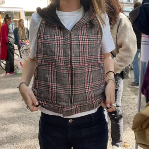 Rutig väst med luva - Säljer en rutig väst i grått, svart, vitt och rött med dragkedja framtill och en luva. Perfekt för lager-på-lager. Snygg detalj med fickor på sidorna. Bara att skriva om du har fler frågor. Kan mötas i Stockholm.