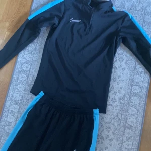 Nike tracksuit - Svart Nike track skit med blåa detaljer nästan helt oanvänd så här av er vid intresse 