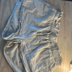 Beiga linneshorts från Lindex - Säljer ett par beiga shorts från Lindex i mjukt linnematerial. De har resår i midjan för extra komfort och en avslappnad passform. Perfekta för varma dagar och enkla att matcha med olika toppar.