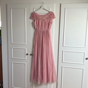 Rosa långklänning med spets och tyll - Rosa långklänning från Vila med spetsdetaljer upptill och tyllkjol. Använd 1 gång, bra skick.
