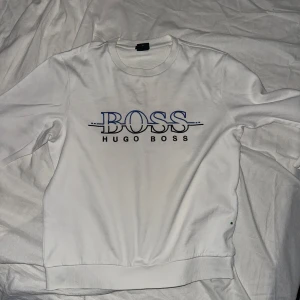 Vit sweatshirt från Hugo Boss  - Säljer en vit sweatshirt från Hugo Boss med stor BOSS-logga framtill. Tröjan har rund halsringning och långa ärmar. Perfekt för en stilren och avslappnad look.passar S med 