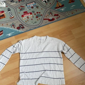 Vit randig tröja från MARINE - Säljer en vit långärmad tröja från MARINE i storlek XL. Tröjan har tunna mörkblå horisontella ränder och ribbade muddar vid hals, ärmslut och nederkant. Perfekt för en avslappnad stil. Köptes för ca 3 år sedan men är knappt använd. Säljer då jag tyvärr aldrig använder den. Jag tror att någon annan kommer få väldigt bra nytta av den. Den är i XL men är hyfsat liten i storleken. Köparen står för frakt om inte annat sägs❤️