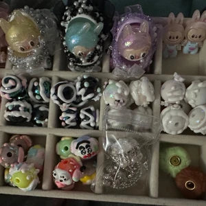 Mixade pärlor till penna lr pyssel - 4 st labubu ansikten med vagn. Båda har hål för penna. Perfekt till beadedpen lr som dekoration på tex tårta lr annat till babyshower. 2 st flat back labubu glow in the dark. 2 st fina handmålade luftballonger med hål för penna. 4 st fluff till penna. 1 st vita superfina handmålade pärlor till penna 16 mm + 10 st i svart. 3 st rosa öppningsbara pärlor passar på penna. 5 st pärlemo med stort hål. 10 st handmålade pärlor med olika ansikten på. 1 fin strass fancy pärla . 