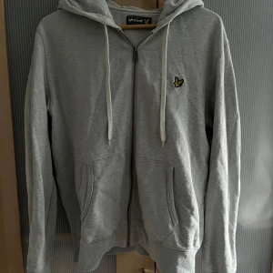 Ljusgrå zip hoodie från Lyle & Scott - Säljer min ljusgråa zip hoodie från Lyle & Scott. Använd men i gott skick (inga defekter). Storlek Large.