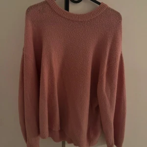 Rosa stickad tröja - Mysig rosa stickad tröja med rund halsringning och långa ärmar. Perfekt för kyligare dagar och enkel att matcha med olika outfits.