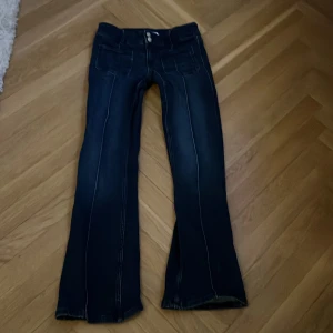 Mörkblå bootcut jeans med dubbla knappar från Gina - Snygga mörkblå jeans med bootcut passform och dubbla knappar i midjan. Jeansen har fram- och bakfickor samt markerade sömmar för en cool look. Perfekta för dig som gillar en klassisk men trendig stil.