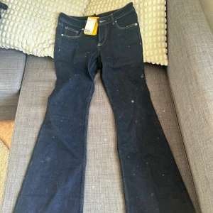 Mörkblå bootcut jeansbyxor - Säljer ett par mörkblå jeansbyxor med bootcut passform. Klassisk femficksmodell med kontrastsömmar och hög midja. Perfekta för dig som gillar en retroinspirerad stil. Märkeslapp syns i linningen. Storlek 42 men skulle säga att den mer passar 38
