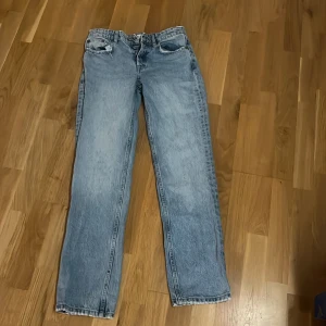 Ljusblå raka jeans - Säljer ett par ljusblå jeans med rak passform och klassisk femficksdesign. Jeansen har normalhög midja och stängs med knapp och dragkedja. Perfekta för en avslappnad och stilren look.