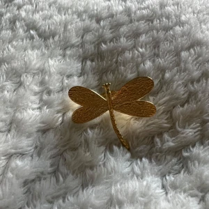 Guldfärgad ring med trollslända - Unik och trendig ring i guldfärg formad som en trollslända. Ringen har en snygg textur på vingarna och är ett riktigt statement-smycke som drar blickarna till sig. Köpt på plick så ingen aning vart den kommer ifrån🥰🙌🏼☺️