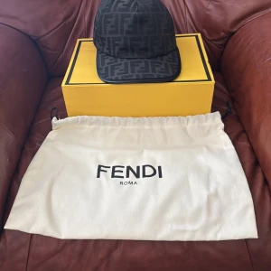 Svart keps från Fendi med monogram - Snygg svart keps från Fendi med klassiskt FF-monogram över hela kepsen. Justerbar baktill och med Fendi-logga broderad på baksidan. Perfekt accessoar för en trendig look.