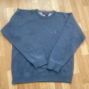 Blå stickad tröja från Tommy Hilfiger - Till salu: Tommy Hilfiger Stickad Tröja ✨  Snygg och stilren stickad tröja från Tommy Hilfiger! 👕 Färg: Gråblå 💙 Storlek: (L) 📏 Skick: Väldigt bra, inga fläckar eller hål! ✅ 	•	Klassisk rund halsringning 🔵 	•	Ribbade muddar och nederkant för perfekt passform 👌 	•	Ikonisk Hilfiger-logo på bröstet.  Perfekt både till vardags och när du vill vara lite extra snygg! ✨  Passa på innan den försvinner! ⚡ 