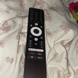 Svart fjärrkontroll med streamingknappar - Säljer en svart fjärrkontroll med knappar för bland annat YouTube, Netflix och Prime Video. Fjärrkontrollen har en rund navigationsknapp i mitten och flera funktionsknappar för smart-TV. Passar till moderna TV-apparater.