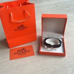Svart  H armband  - Säljer ett stilrent svart armband från H med den ikoniska H-detaljen framtill. Armbandet kommer i originalask och med tillhörande presentpåse och certifikat. Perfekt accessoar för att lyfta din outfit.