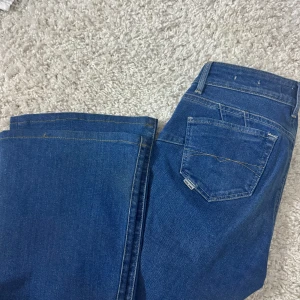 Lågmidjade jeans - Snygga blå jeansbyxor från Salsa Jeans med klassisk femficksdesign och raka ben. Jeansen har normal passform och är tillverkade i ett slitstarkt denimtyg med tydliga sömmar. Perfekta för dig som gillar en tidlös jeansstil. Passar s. 