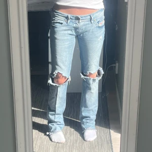 Ljusblåa jeans med hål från disel  - Ljus blåa straight leg jeans från diesel med hål vilket gör dom lite ”luftigare”. Längst ner har ja klippt 4 hack i benets slut för att få de att lägga sig lite mer ”fallande” mot foten ( fick inte plats med bild, men skickar gärna vid fundering) midjemåttet rakt över är ungefär 40 cm och innerbenslängd 80