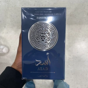 Lataffa Asad Zanzibar EDP 100ml  - Parfymen Asad Zanzibar från Lattafa i en elegant mörkblå förpackning med silverdetaljer och orientaliskt mönster. Eau de Parfum, 100 ml. Doften är inspirerad av Zanzibar och passar dig som gillar exklusiva och kryddiga parfymer.