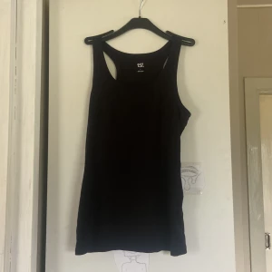 Svart linnetopp från 157, storlek L - En klassisk svart linnetopp från 157 i storlek L. Modellen är ärmlös med breda axelband och rund halsringning. Tillverkad i 100% bomull för en skön och luftig känsla. Perfekt att matcha med jeans eller shorts för en enkel och clean look.