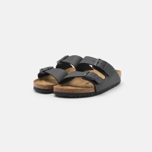 Birkenstock sandaler svarta - Klassiska svarta sandaler från Birkenstock med två breda remmar och justerbara spännen. Fotbädden är i kork och sulan är platt och svart. Perfekta för sommardagar och enkel att matcha med allt. Endast använda 1-3 ggr. 