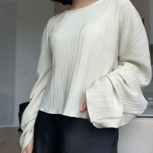 Vit plisserad blus från Gina Tricot - Superfin vit plisserad blus från Gina Tricot i storlek XXS. Blusen har vida, långa ärmar och en croppad passform. Materialet är lätt och känns luftigt, perfekt för vår och sommar. Snyggt ribbat tyg som ger en modern look.