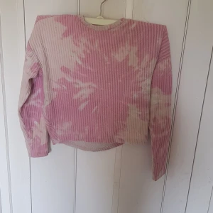 Rosa ribbad tröja från H&M - Superfin ribbad tröja från H&M i rosa och vitt batikmönster. Tröjan har lång ärm och är tillverkad i mjuk bomull, perfekt för dig som gillar en chill och trendig stil. Rund halsringning och relaxed fit gör den extra skön.