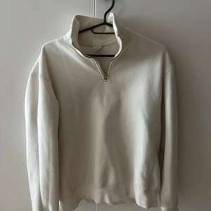 Tröja  - Säljer en stilren vit sweatshirt från Zara med half zip och hög krage. Tröjan har långärmad passform och är gjord i mjuk bomull, perfekt för lager-på-lager. Enkel och clean look som funkar till allt. Snygg att matcha med jeans eller mjukisbyxor.