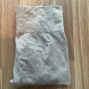 Grå seamless leggings från Gymshark - Snygga grå träningstights från Gymshark med diskret mönster och hög midja. De har scrunch-detalj bak för extra passform. Perfekta för träning eller chill dagar. Har en liten prick som knappt syns (se bild) annars fint skick. 