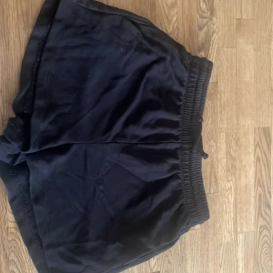 Svarta loose shorts med resårmidja - Svarta shorts med loose passform och bred resår i midjan. Mjukt material som känns skönt mot huden och passar perfekt för chill dagar eller träning. Klassisk look utan synliga loggor eller detaljer, enkel och stilren design.