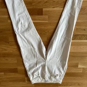 Vita raka jeans från Zara - Säljer ett par vita jeans från Zara med raka ben och råa, fransiga benslut. Byxorna har klassisk femficksdesign och är tillverkade i ett kraftigare bomullstyg. Perfekta för en clean och fräsch look.