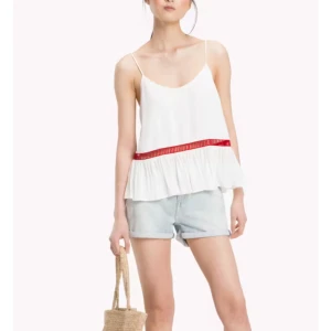 Tommy Hilfiger strl M (10) vitt volang linne - Supersöt vit linnetopp med tunna axelband och volang från Tommy Hilfiger. Toppen har en röd, genombruten detalj som markerar midjan och ger en extra touch. Luftig och flowy passform, perfekt för varma dagar och chill vibes. Strl 10 motsvarar M. Jättefint skick! 
