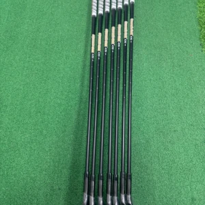 Dynamic Gold 105 Golfklubbor - Bilderna visar ett set golfklubbor, Dynamic Gold 105 S300, med svarta skaft och skyddsplast kvar på klubbhuvudena. Perfekt för dig som vill ta ditt golfspel till nästa nivå med stilrena och moderna klubbor.