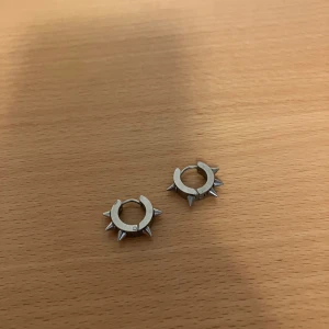 Silvriga/grå örhängen med nitar - Coola silvriga hoops med små spikes runt hela ringen. Perfekta för dig som vill ha en edgy och alternativ stil.