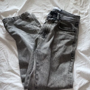 Grå jeans med tvättad look från FSBN - Säljer ett par grå jeans från FSBN med snyggt tvättad effekt och klassisk femficksdesign. Jeansen har raka ben och normal passform, perfekta för en avslappnad stil. Materialet är robust denim som håller länge. 