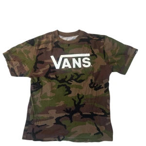 Camouflage t-shirt från Vans - Snygg t-shirt från Vans med klassiskt camouflagemönster i grönt, brunt och svart. Storlek L, 12-14. Stor vit Vans-logga på bröstet. T-shirten har rund hals och korta ärmar, perfekt för en avslappnad streetstyle-look.