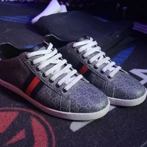 Gucci sneakers med GG-mönster - Snygga Gucci sneakers i grått med klassiskt GG-mönster, vita snören och röd-svart rand på sidan. Baksidan har metallicdetaljer i rött och svart med Gucci-logga. Yttermaterial i canvas och detaljer i skinn. Perfekta för dig som vill sticka ut med lyxig streetstyle.