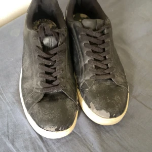 Svarta sneakers från Pull&Bear - Svarta sneakers från Pull&Bear med klassisk design och vita sulor. Skorna har snörning och är tillverkade i syntetmaterial med en rund tå. Perfekta för dig som gillar en enkel och stilren look till vardags.