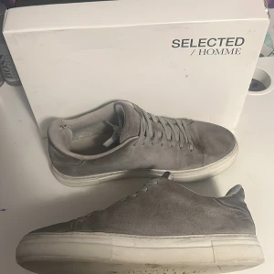 Grå mockasneakers från Selected Homme - Säljer ett par selected Homme skor som jag knappt använder längre. Pris kan diskuras