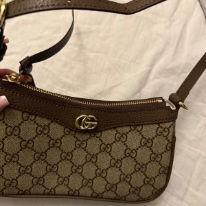 Gucci Ophidia bag - Gucci Ophidia Small Shoulder Bag – 9000 kr (nypris ca 14 000 kr)  Säljer min äkta Gucci Ophidia i klassiskt GG Supreme canvas med bruna läderdetaljer och guldfärgad hardware. Väskan är köpt i Gucci-butiken i Paris och är i mycket fint skick – sparsamt använd och väl omhändertagen.  👜 Nypris: ca 14 000 kr 💸 Mitt pris: 9000 ( kan diskuteras vid snabb affär) 📦 Kvitto finns  