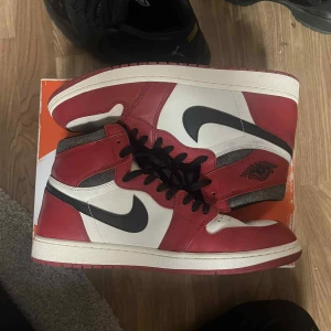 Nike Air Jordan 1 Chicago Highs - Säljer ett par ikoniska Nike Air Jordan 1 Highs i Chicago-färg. Skorna har röd, vit och svart färg med klassisk svart swoosh och vingar-logga på sidan. Ovandelen är i skinn och de har svarta snören samt röd yttersula. Perfekta för dig som vill sticka ut med en tidlös sneaker.