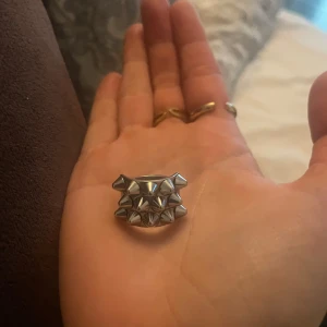 Edblad ring  - Cool ring i silverfärgad metall med flera spetsiga nitar runt hela ringen. Ger en edgy och alternativ vibe, perfekt för dig som gillar att sticka ut. Ringen har en bred design och är riktigt statement.
